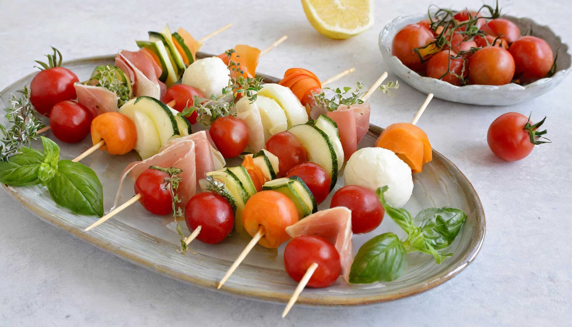 Apéritif diététique avec des brochettes de fruits et légumes, melon, tomates cerises et jambon cru